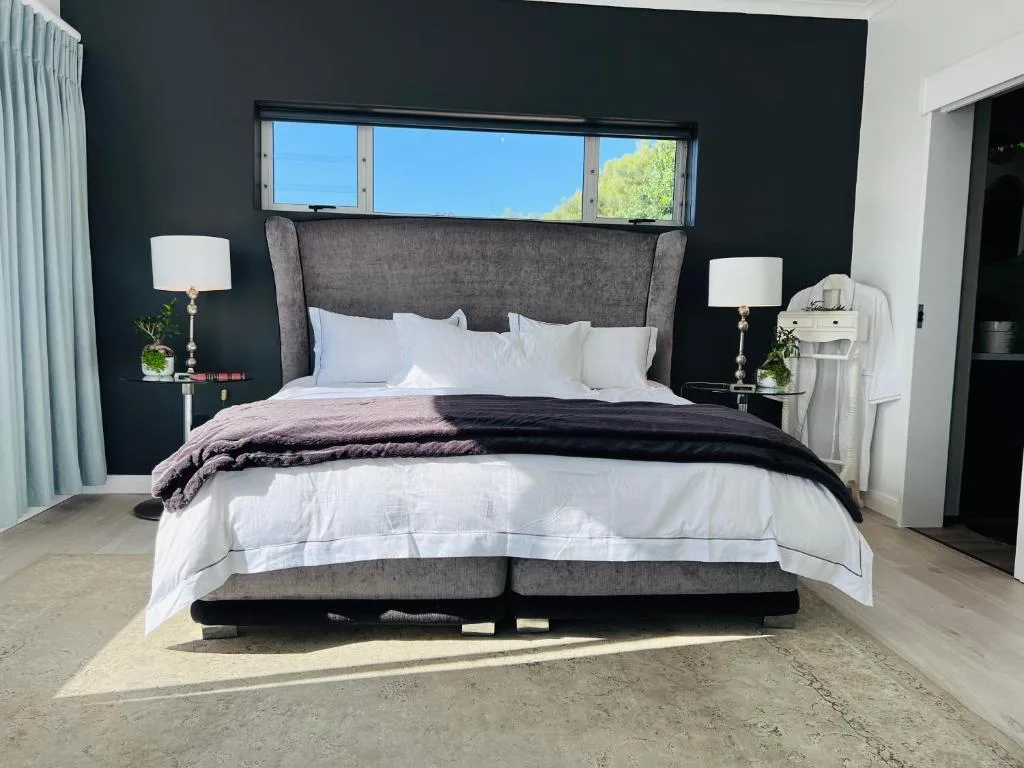 Modern bedroom with gray upholstered bed, white linens, dark accent wall