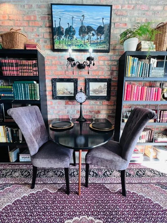 Stylish interior with round black table, upholstered chairs, brick walls, and bookshelves