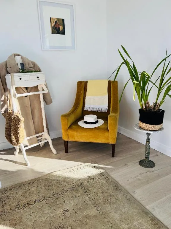 Mustard chair with hat, clothing rack, and potted plant decor