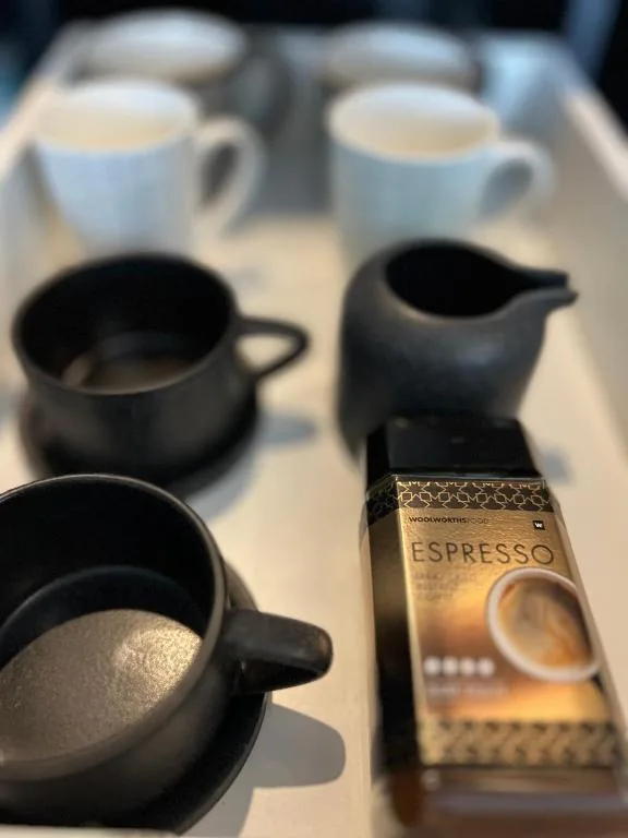 Coffee service setup with espresso packet, mugs, and milk pitchers