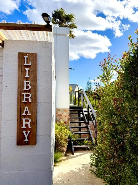 White-walled accommodation entrance with Library signage and wooden stairs