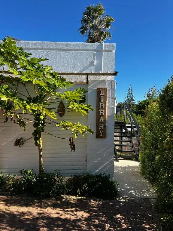White cottage entrance with Library signage and palm trees overhead
