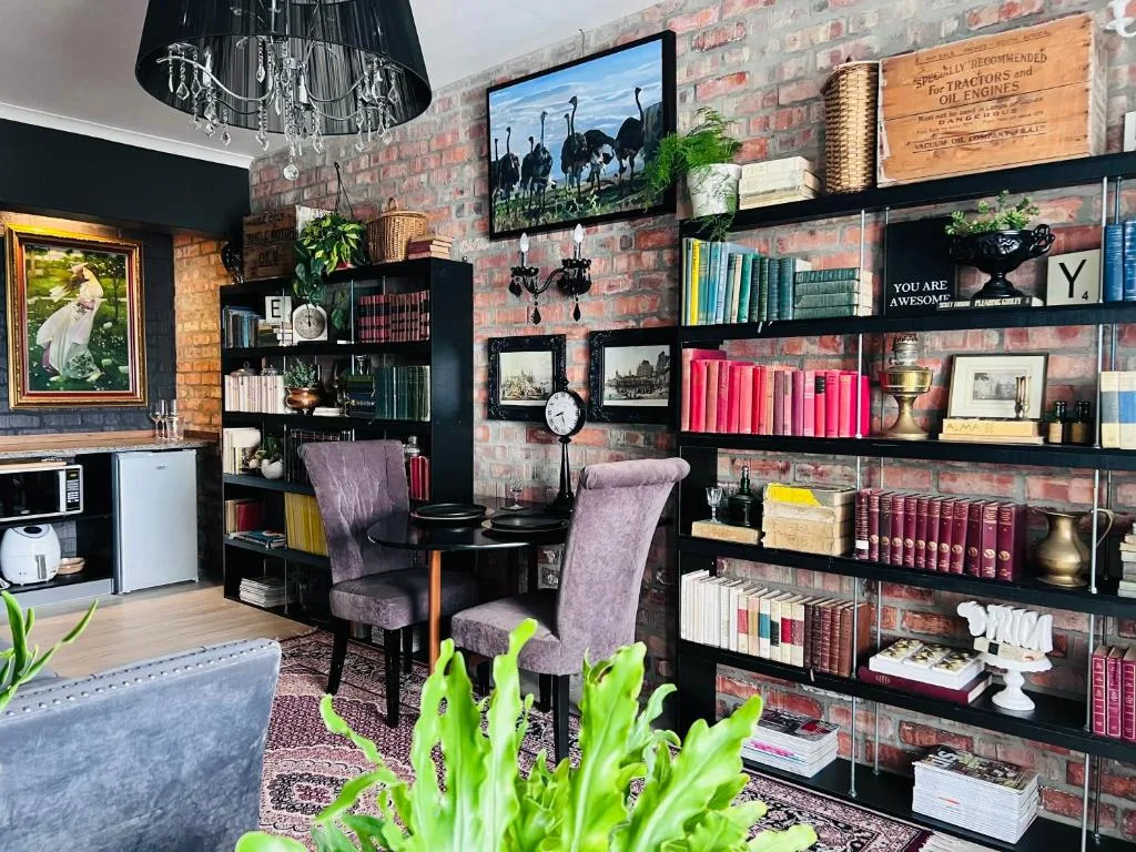 Open-plan lounge with purple chairs, brick walls, black shelving, and decorative accents