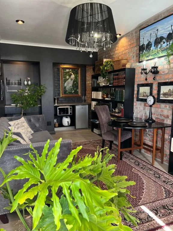 Elegant lounge with gray sofa, black chandelier, brick feature wall, and decorative shelving