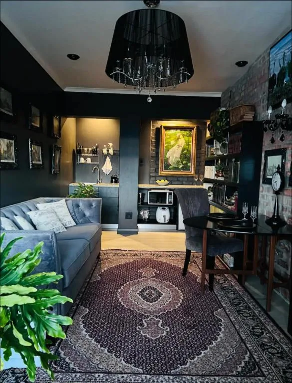 Dark navy lounge with blue sofa, chandelier, shelving, and decorative artwork