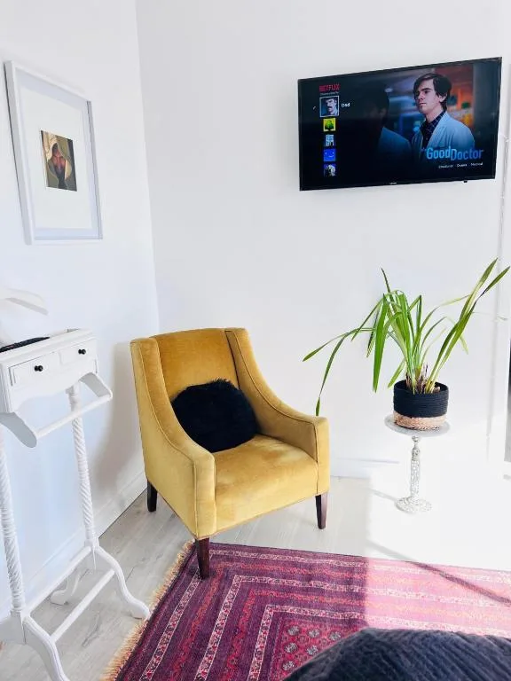 Modern lounge with mustard armchair, wall-mounted TV, and potted plant