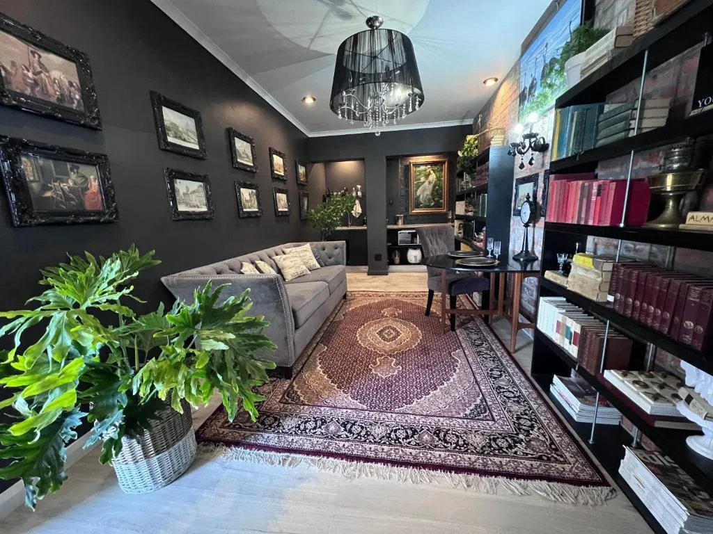 Elegant lounge with gray sofa, dark walls, framed artwork, and decorative plants