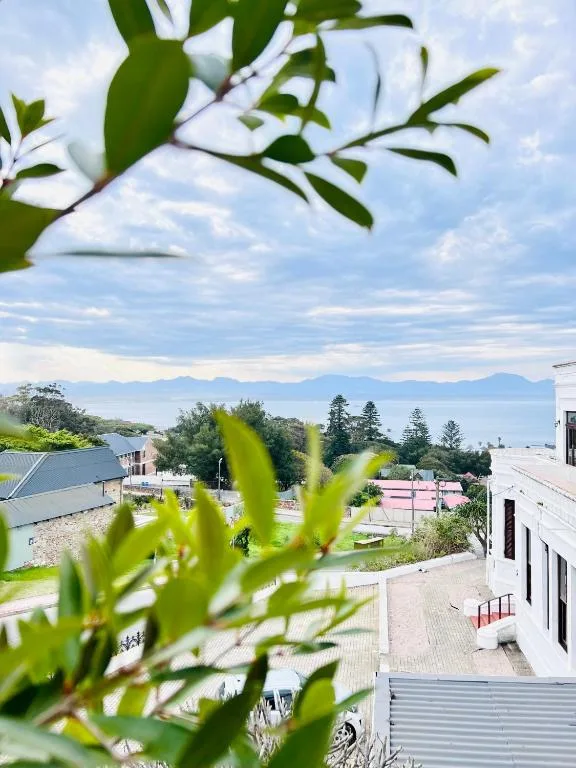 Mountain and ocean vista framed by green foliage from property balcony