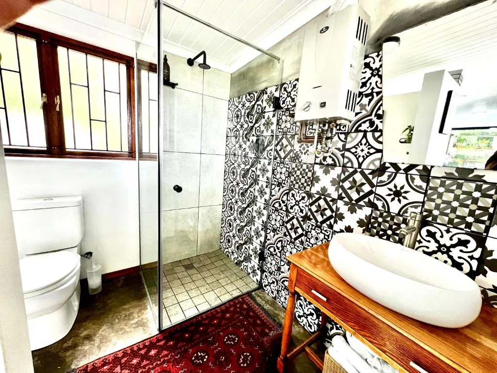 Modern bathroom with patterned black and white tiles, walk-in shower, wooden vanity