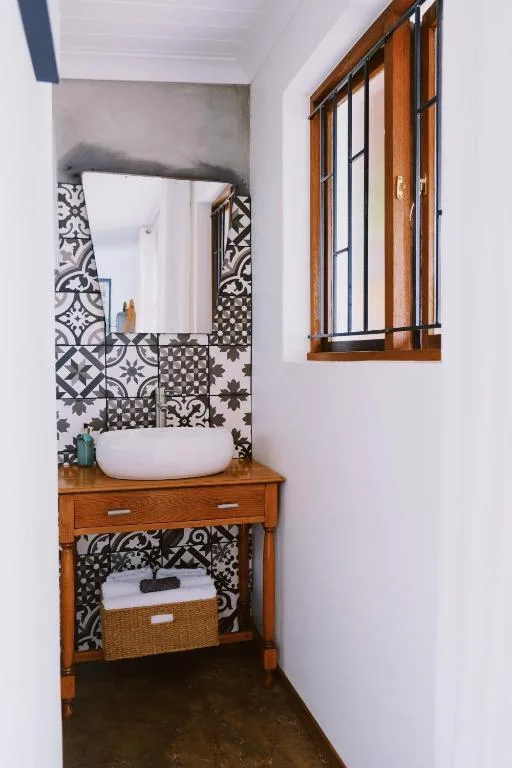 Modern bathroom with round white sink, wooden vanity, patterned tile backsplash
