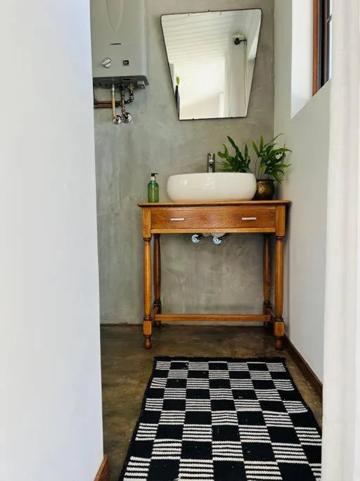 Modern bathroom with wooden vanity, vessel sink, and geometric floor mat