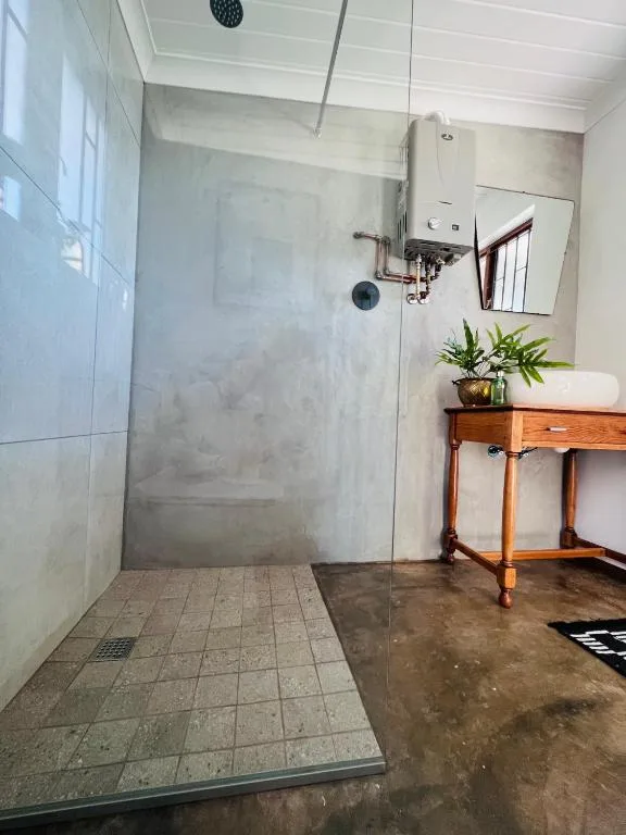 Modern walk-in shower with glass enclosure and rainfall showerhead in bright bathroom