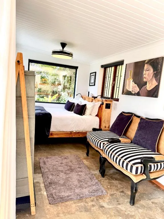 Spacious bedroom with queen bed, striped bench seating, and garden views