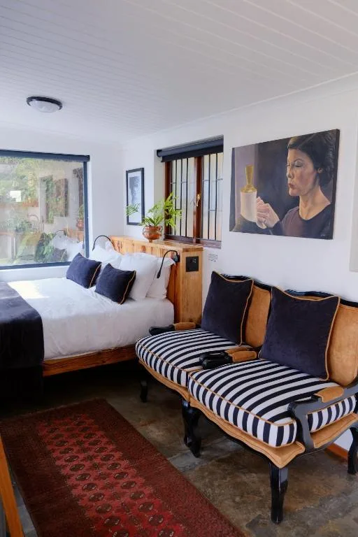 Bedroom with wooden bed, striped seating chair, and artwork on white walls