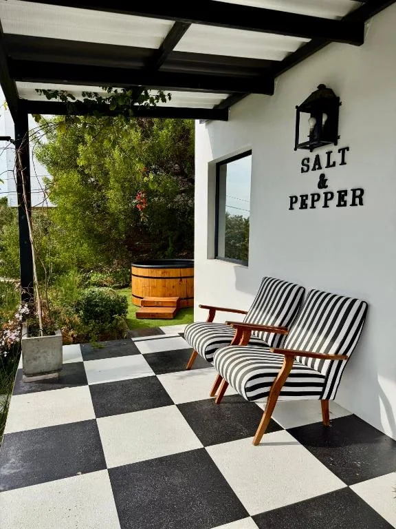 Covered patio with striped chairs overlooking garden and wooden hot tub