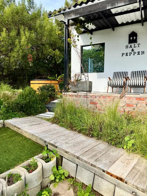 Outdoor patio with striped chairs, pergola, and manicured garden area