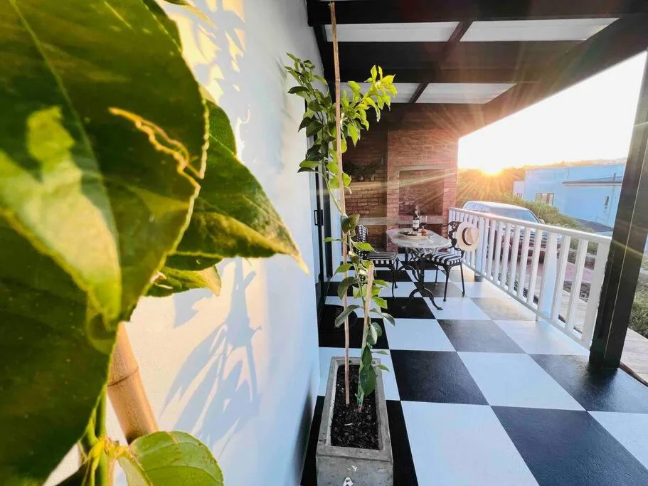 Modern covered patio with checkered flooring and coastal lagoon views at sunset