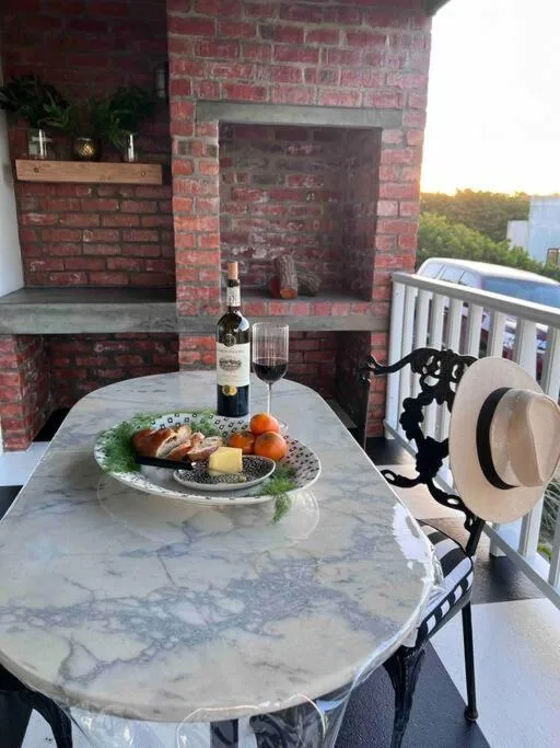 Marble outdoor dining table with wine and charcuterie, brick fireplace backdrop