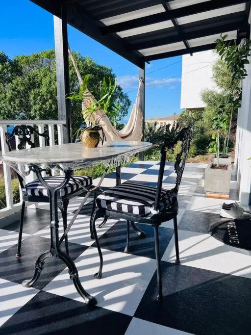 Shaded patio with dining table, chairs, and hammock overlooking gardens