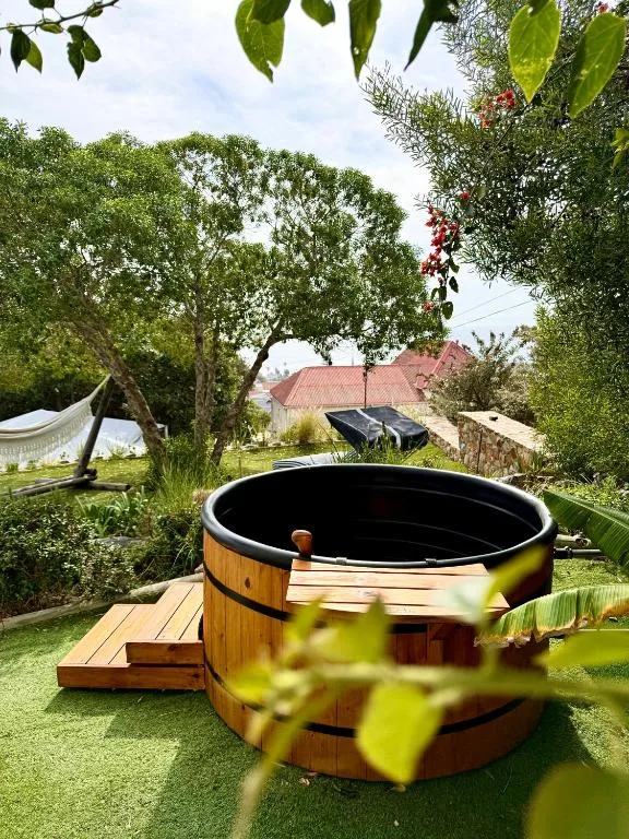 Wooden hot tub nestled in lush garden with mature trees and property views