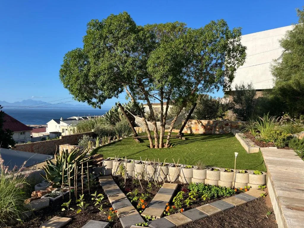 Lush garden with mature tree, ocean view, and landscaped grounds at sunset