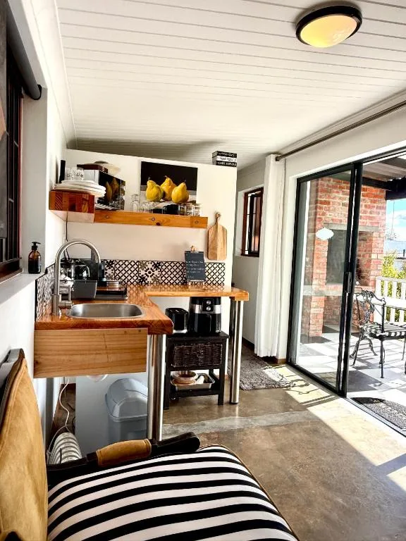 Compact kitchen with wooden counter, patterned backsplash, and open shelving above sink