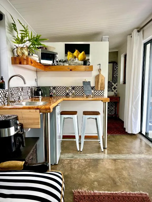 Modern kitchen with wooden counters, white bar stools, and decorative shelf
