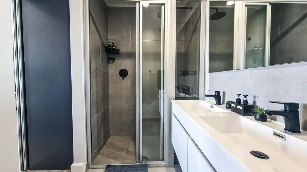 Modern bathroom with dual vanity sink and walk-in shower enclosure