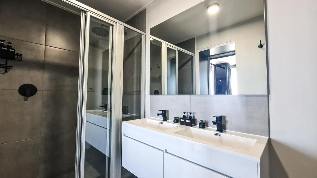 Modern bathroom with double vanity, large mirror, and walk-in shower