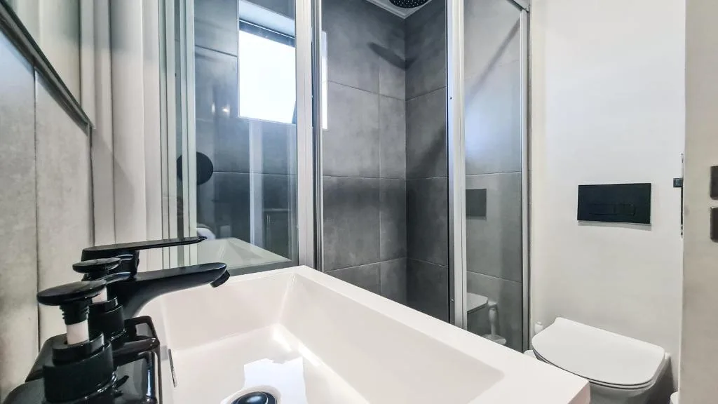Modern bathroom with white bathtub, black faucet, and glass shower enclosure