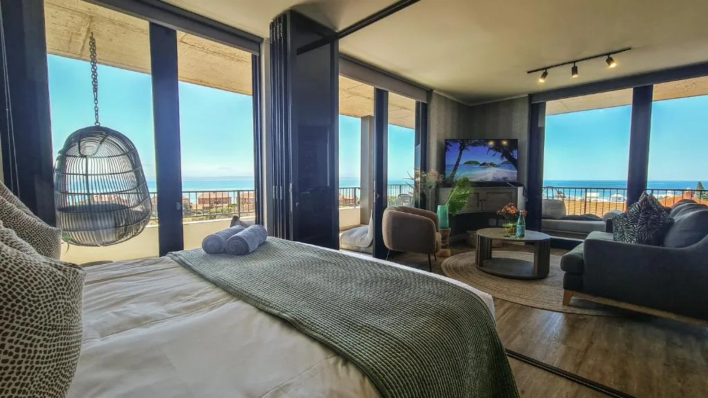 Luxury bedroom with ocean view, hanging chair, and coastal decor