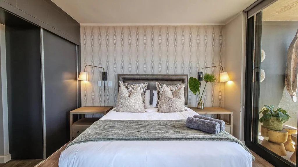 Modern bedroom with king bed, patterned wallpaper, pendant lights, and sliding door access