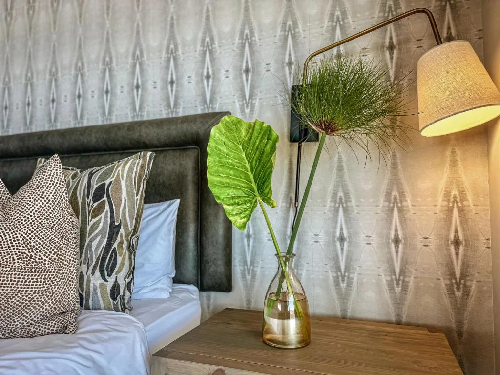 Modern bedroom with upholstered headboard, patterned pillows, and bedside flowers