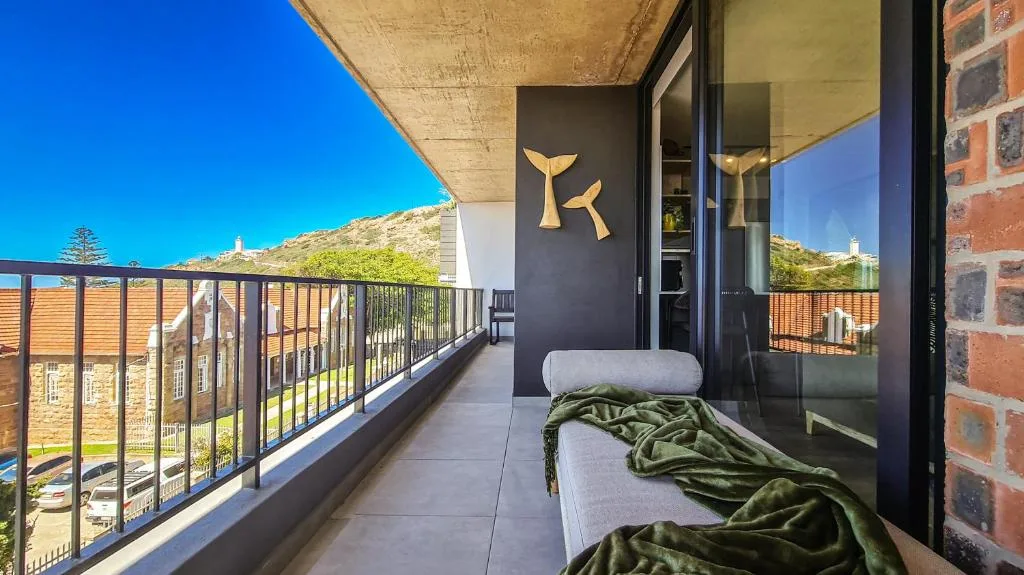 Modern balcony with loungers overlooking green hills and clear blue sky