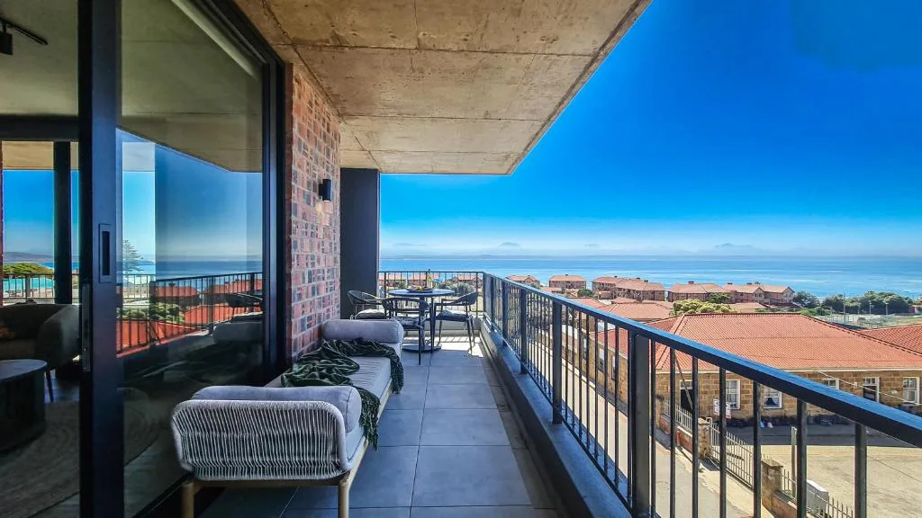 Spacious balcony with sea view, lounge chairs, and coastal landscape vista