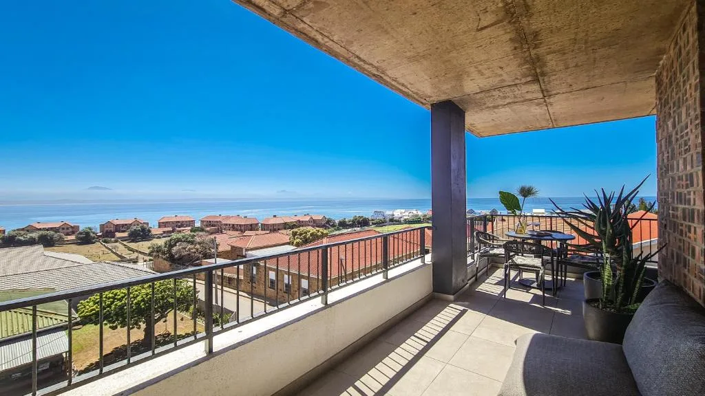 Spacious balcony with ocean and coastal town views, modern furnishings