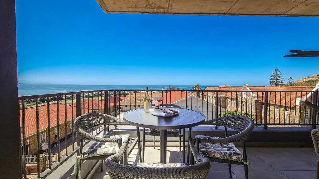 Elevated deck with ocean views, outdoor dining table, and comfortable seating