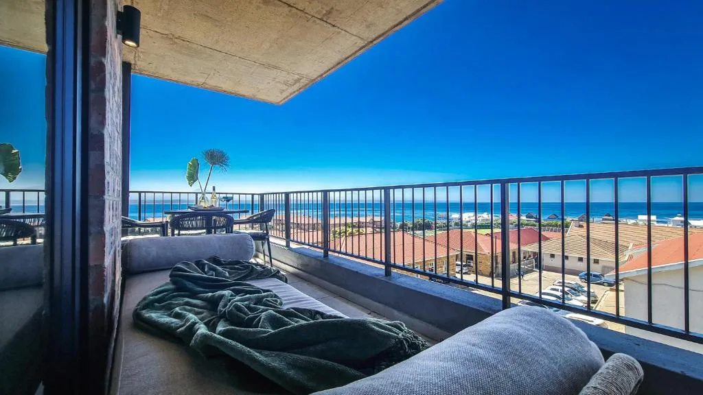 Elevated balcony with loungers overlooking coastal town and ocean horizon