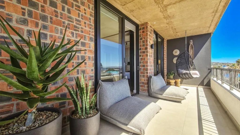 Spacious balcony with outdoor seating, potted plants, and water views