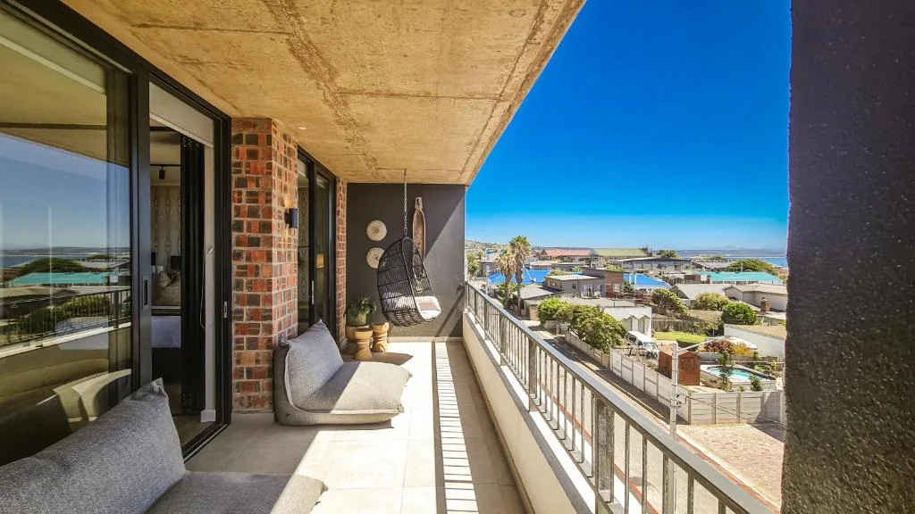 Spacious balcony with hanging chair overlooking coastal town and ocean