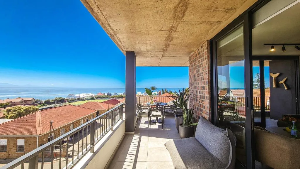 Expansive penthouse balcony with seating overlooking coastal town and ocean