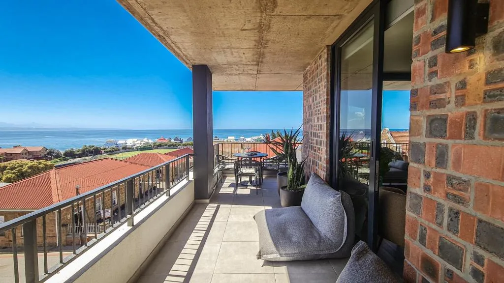 Spacious balcony with seating overlooking ocean and coastal town landscape