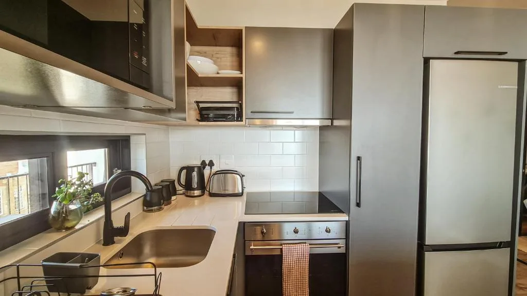 Modern kitchen with stainless steel appliances, white subway tiles, and wood countertops