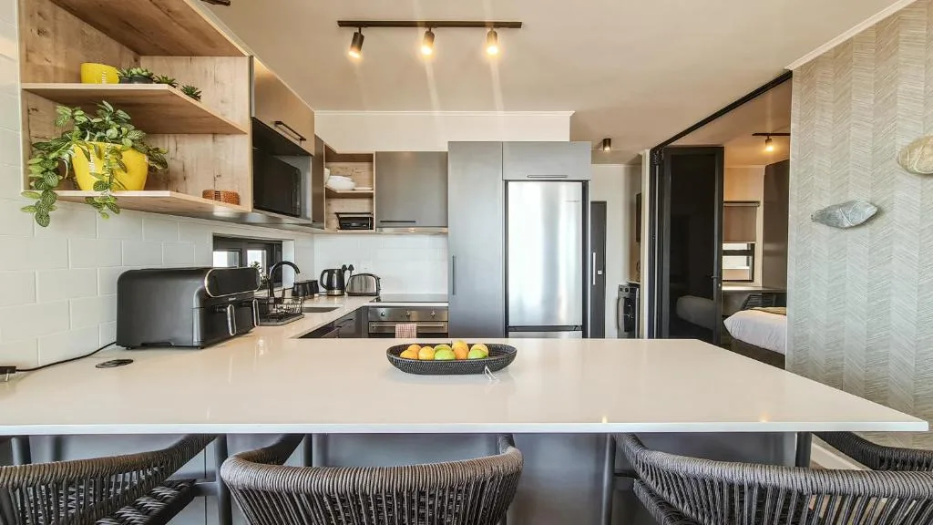 Modern open-plan kitchen with stainless steel appliances and white countertop
