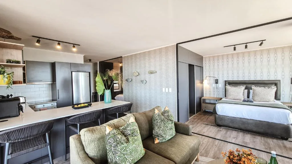 Open-plan lounge with sofa, kitchen and bedroom visible in background