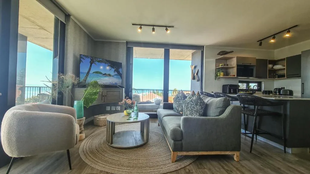 Modern lounge with gray sofas, round coffee table, and ocean views through large windows