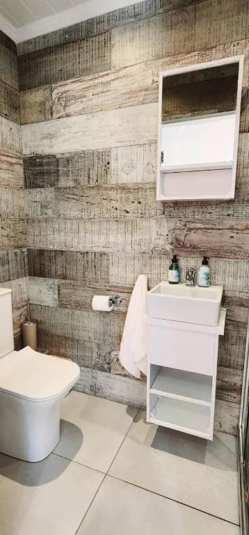 Modern bathroom with white vanity, toilet, and textured brick accent walls
