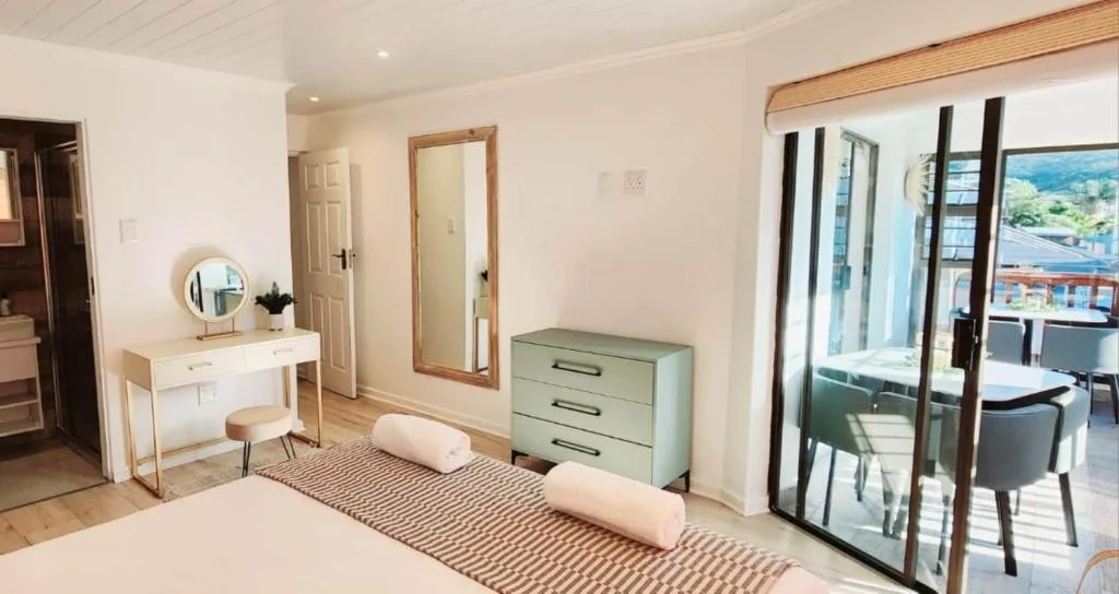 Bright bedroom with bed, vanity desk, and glass doors to deck