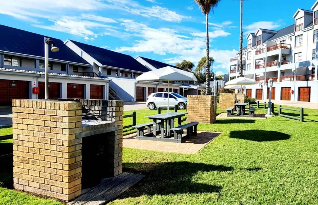 Spacious lawn with picnic tables, braai area, and outdoor seating