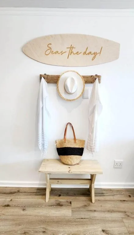 Entryway wall decor with wooden sign, hat, and woven basket storage